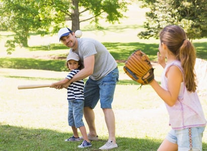 Family of three playing baseball in the park