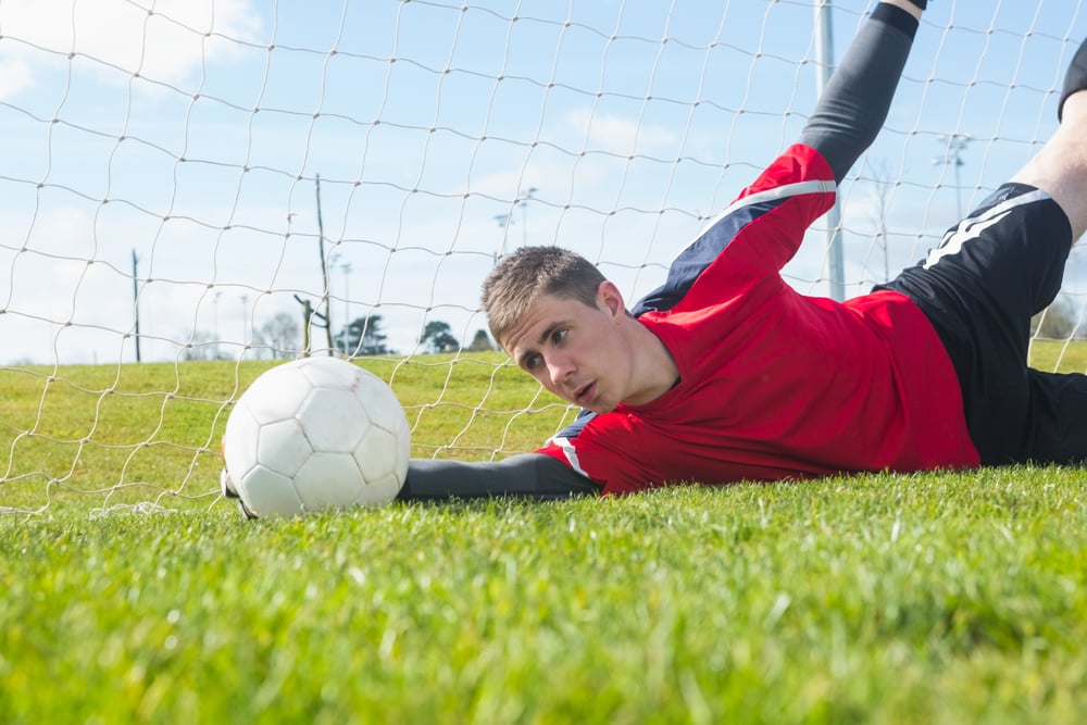 Goalkeeper in red making a save during a match