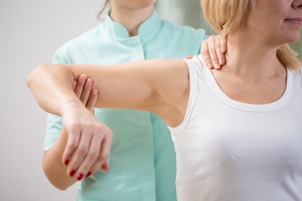 Physical therapist diagnosing patient with painful arm