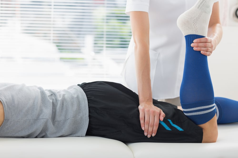 Physiotherapist working on the leg of young man